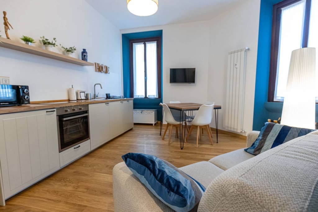 La cucina lineare con forno e mensole, aperta sul soggiorno