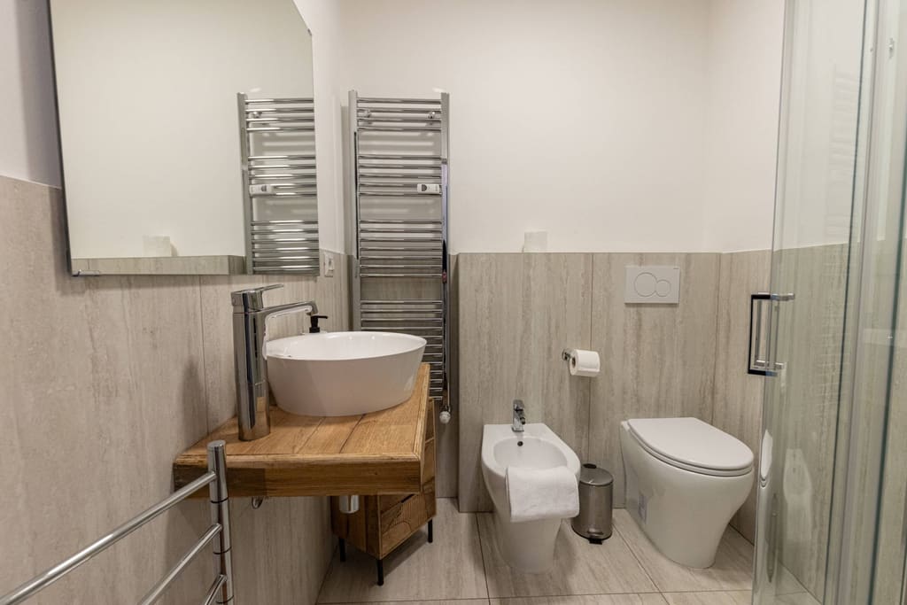 Il bagno con lavabo in appoggio su piano in legno, sanitari e box doccia