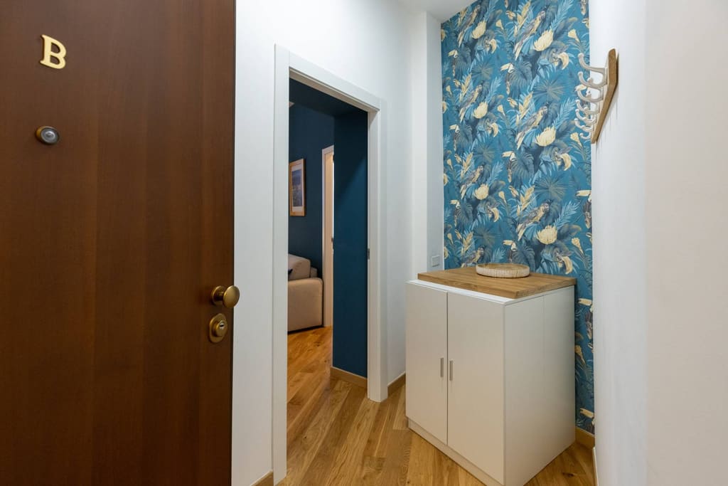 L'ingresso con la carta da parati a foglie e la porta B